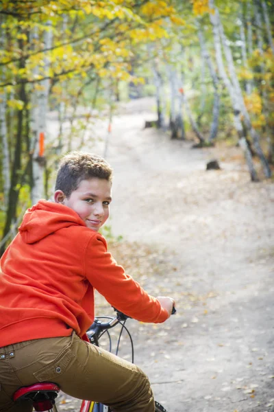 Im herbstlichen Wald strahlend sonniger Tag Junge fährt Fahrrad. — Stockfoto