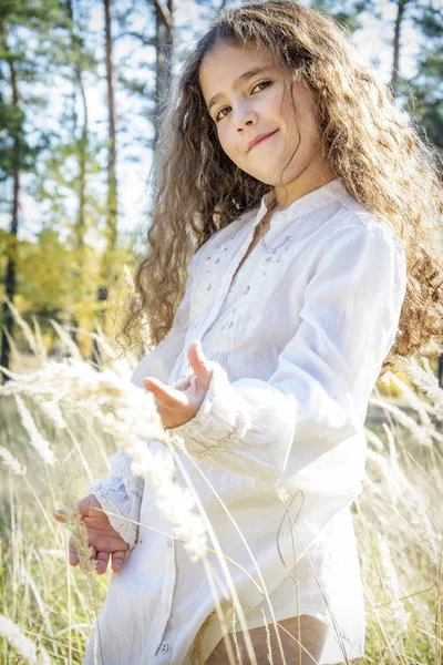 En el bosque de otoño en un claro una pequeña chica rizada hermosa —  Fotos de Stock