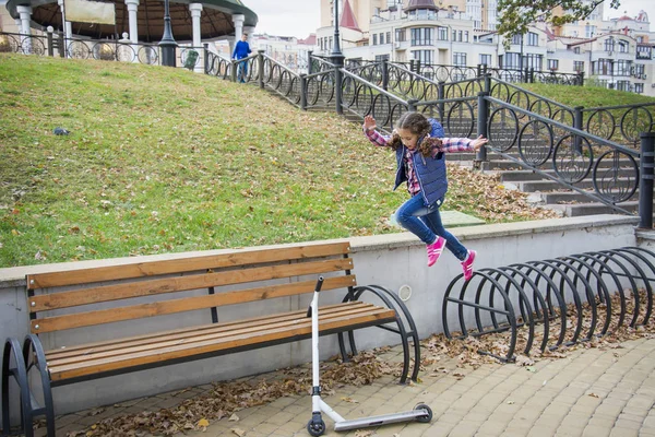 In the park on a sunny day, a little girl jumps over obstacles. — Stock Photo, Image