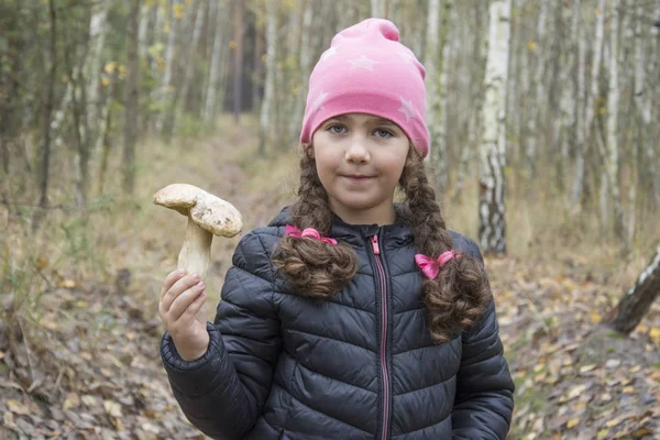 In het bos houdt een meisje een porcini paddestoel in haar hand.. — Stockfoto