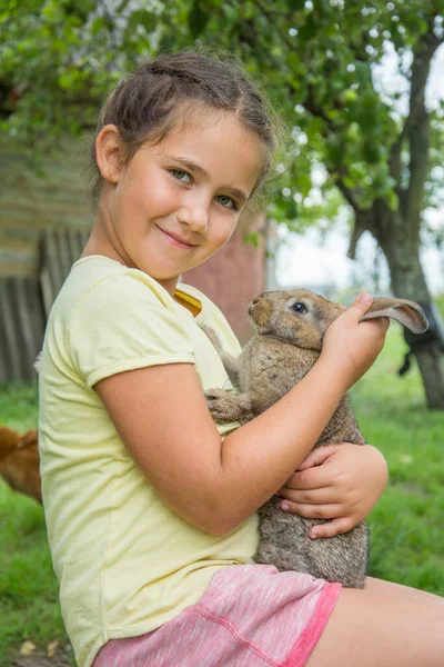 Tarde Verano Una Niña Sienta Jardín Sostiene Conejo Gris Sus — Foto de Stock