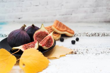 Bir tabak, çerezler ve parlak bir bulanık zemin, sarı yapraklar üzerine meyveleri kesim incir dilimleri.