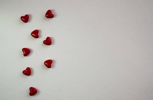 White background red small hearts. Top view with space for your greeting. Valentine's day decoration with copy space