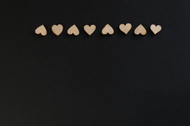 A border from wooden hearts on a chalk black board, black background, there is a place for text. heart for valentines concept clipart