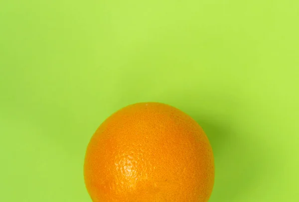 Una naranja sobre un fondo verde. Hay un lugar para el texto . — Foto de Stock