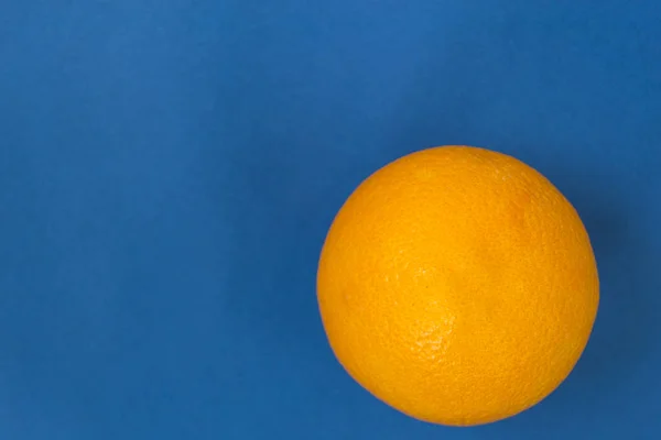Uma laranja num fundo azul. Há um lugar para texto . — Fotografia de Stock