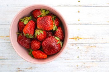 Hafif bir arka plan üzerinde pembe bir kase kırmızı çilek.