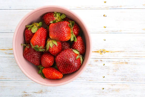 Hafif bir arka plan üzerinde pembe bir kase kırmızı çilek.