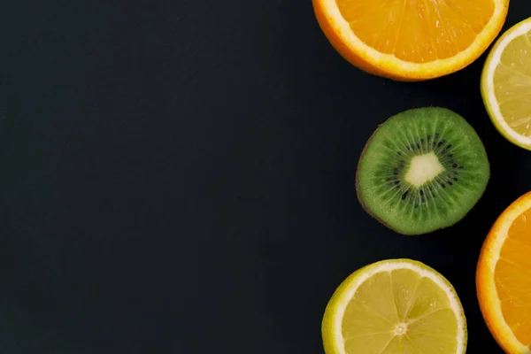 Frutas frescas de colores sobre un fondo oscuro. Naranja, mandarina, kiwi, limón. Fondo de fruta. Concepto de comida de verano . — Foto de Stock