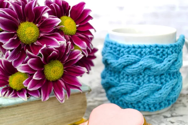 Crisantemo granate. Flores de color rosa con un centro amarillo se encuentran en el libro. Muy cerca hay una taza de té y un delicioso café. Galletas de jengibre rosa son como el postre . —  Fotos de Stock