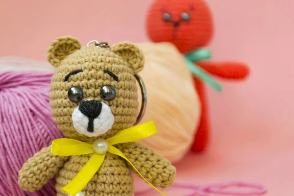 Un ours brun tricoté est assis sur un fond rose, derrière il y a une boule de fil rose et jaune, et un lièvre tricoté orange se tient derrière le fil. Il y a une place pour le texte . — Photo