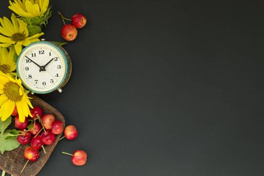 Siyah bir arka plan üzerinde bir sepet içinde sarı ayçiçeği ve çiçek ve kırmızı elma bir buket yanında eski çalar saat. Anneler Günü ya da kadınlar. Tebrik kartı Günaydın, gün. Yaz kavramı, ya da Eylül