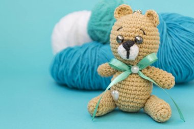 Bir kahverengi örme ayı pembe ve sarı iplik bir top, ve bir turuncu örme tavşan iplik arkasında duruyor, arka plan üzerine oturur. Metin için bir yer var.