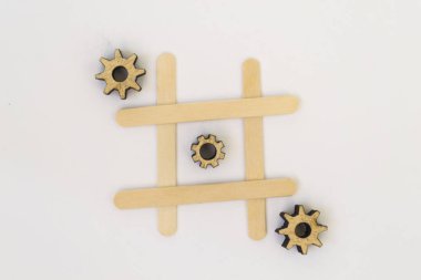 Mekanizmadan üç ahşap dişliler beyaz bir arka plan üzerinde bir ızgara, tic tac toe oyununda bir satır da bir satır yalan.