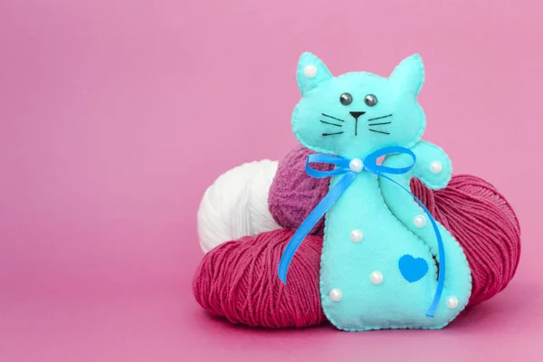 Juguete para niños gato hecho de fieltro sobre un fondo de color junto a las bolas de hilo . —  Fotos de Stock
