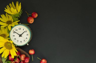 Siyah bir arka plan üzerinde bir sepet içinde sarı ayçiçeği ve çiçek ve kırmızı elma bir buket yanında eski çalar saat. Anneler Günü ya da kadınlar. Tebrik kartı Günaydın, gün. Yaz kavramı, ya da Eylül