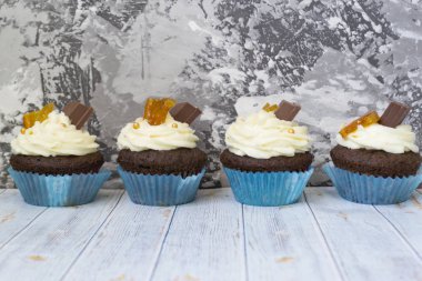 Vanilya tereyağı frosting ve altın kırıntıları, çikolata ve limon ile Çikolata cupcakes. Metin için bir not var.