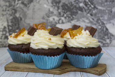 Vanilya tereyağı frosting ve altın kırıntıları, çikolata ve limon ile Çikolata cupcakes. Metin için bir not var.