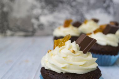 Vanilya tereyağı frosting ve altın kırıntıları, çikolata ve limon ile Çikolata cupcakes. Metin için bir not var.