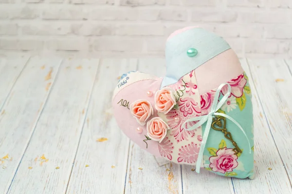 Un corazón textil con un romántico color de flores sobre un simple fondo de madera clara. enfoque selectivo. Estilo elegante Shabby . — Foto de Stock