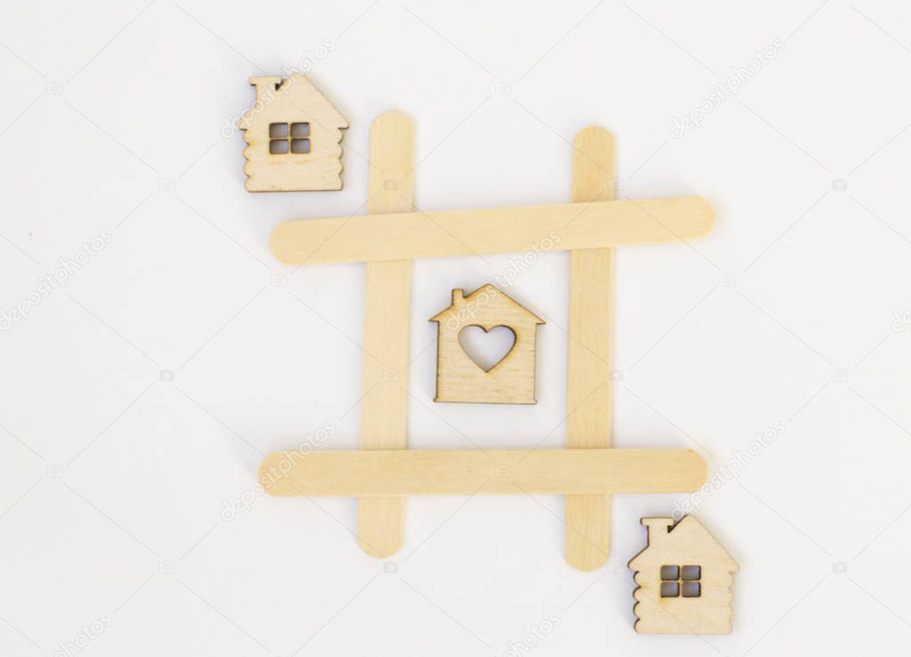 Three wooden houses lie in a row in the game of tic-tac-toe, in a grid on a white background. Concept home, cozy home