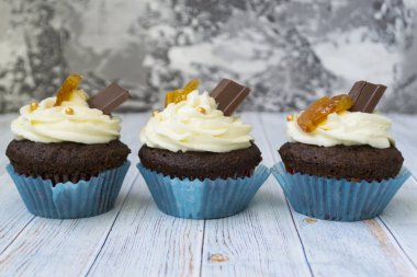 Vanilya tereyağı frosting ve altın kırıntıları, çikolata ve limon ile Çikolata cupcakes. Metin için bir not var.