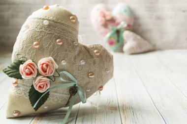 Basit bir ışık ahşap arka plan üzerinde romantik bir çiçek rengi ile üç tekstil kalpleri. seçici odak. Metin için bir yer var.