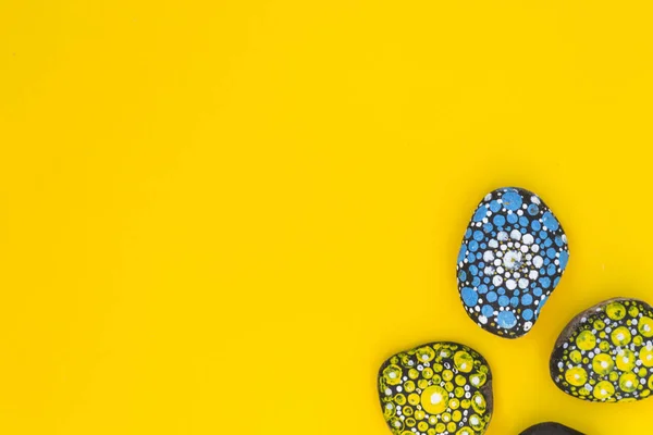 Mit farbigen Farbsteinen bemalt liegen auf gelbem Grund. Es gibt einen Platz für Text. — Stockfoto