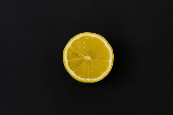 Round slice of yellow lemon, on a black background. — Stock Photo, Image