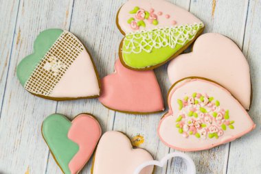 Pembe ve renkli Gingerbread ve bal kek ve kalp şeklinde çerezler açık ahşap arka planda dağınık bir kazık yalan. Yakınlarda pişirme için beyaz kalıplar vardır. Metin için yerleştirin. Aşk kavramı, annenin
