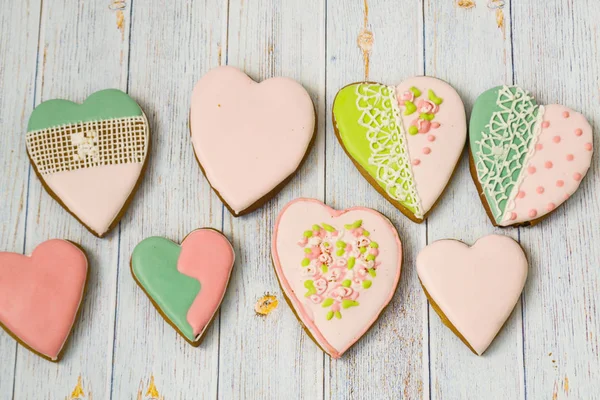 Pink and colored gingerbread and honey cakes and biscuits. Heart-shaped lie on a light wooden background. Patern. Place for text. The concept of love, mother\'s day, cooking,