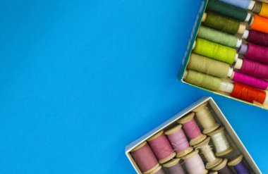 Renkli dikiş ipler mavi bir arka planda satır gradyan bir kutuda yatıyor. Metin için bir yer var.