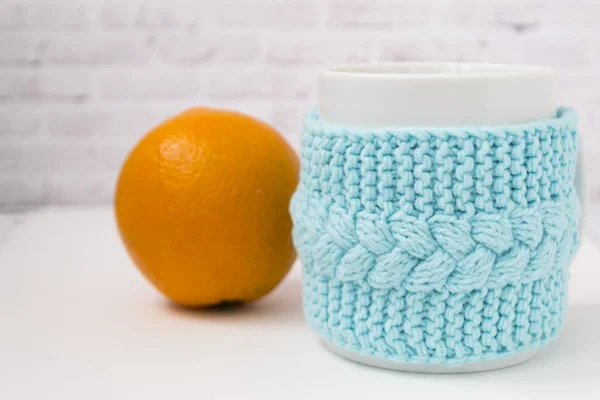 Una taza en una caja azul de punto con una mandarina naranja sobre un fondo claro. El concepto de confort, relajación, comida saludable. Estilo escandinavo. Hay un lugar para la prueba . —  Fotos de Stock