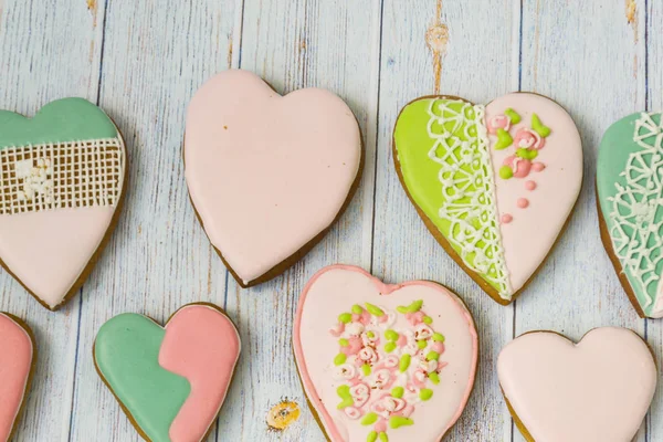 Pink and colored gingerbread and honey cakes and biscuits. Heart-shaped lie on a light wooden background. Patern. Place for text. The concept of love, mother\'s day, cooking,