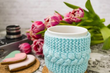 Eski bir kamera ve pembe çiçekler lale ve tatlılar, bir dokusal masada Gingerbread ile bir örme mavi durumda çay beyaz bir fincan.