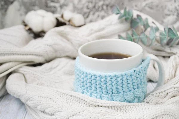 Taza blanca con té en un marco azul de punto y envuelto en un tejido a cuadros de punto blanco. En el fondo, ramitas de eucalipto y algodón. Desayuno en la cama. Acogedor . —  Fotos de Stock