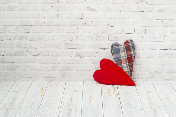 Dois corações feitos à mão do suporte de tecido xadrez em um fundo de tijolo leve, e em um contexto leve de uma mesa de madeira. O conceito de amor, parabéns, borboleta de trabalho manual . — Fotografia de Stock