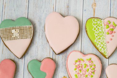 Pink and colored gingerbread and honey cakes and biscuits. Heart-shaped lie on a light wooden background. Patern. Place for text. The concept of love, mother's day, cooking, clipart