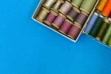 Renkli dikiş ipler mavi bir arka planda satır gradyan bir kutuda yatıyor. Metin için bir yer var.