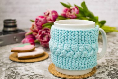 Eski bir kamera ve pembe çiçekler lale ve tatlılar, bir dokusal masada Gingerbread ile bir örme mavi durumda çay beyaz bir fincan.