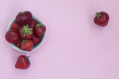 Bir tabak içinde Olgun kırmızı çilek. Pembe arka plan. Vitaminler ile gıdalar.