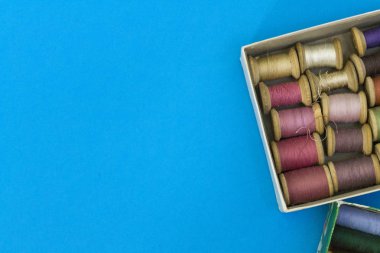 Renkli dikiş ipler mavi bir arka planda satır gradyan bir kutuda yatıyor. Metin için bir yer var.