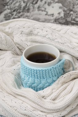 Beyaz bir örme mavi çerçeve içinde çay ile kupa ve beyaz örme ekose sarılmış. Arka planda, okaliptüs ve pamuk çipler. Yatakta kahvaltı. Rahat.