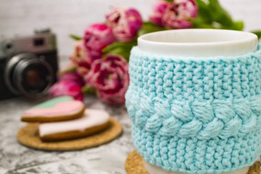 Eski bir kamera ve pembe çiçekler lale ve tatlılar, bir dokusal masada Gingerbread ile bir örme mavi durumda çay beyaz bir fincan.