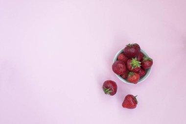 Bir tabak içinde Olgun kırmızı çilek. Pembe arka plan. Vitaminler ile gıdalar.