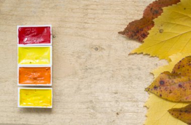 Sarı ağaç yapraklarıyla sonbahar arka planı, sarı, kırmızı, turuncu suluboya ahşap kulübelerde yatıyor..