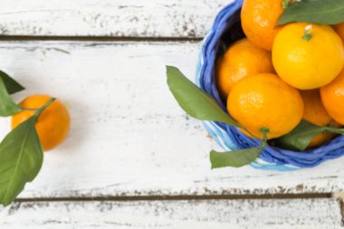 Mandalina portakal, clementines, narenciye, yeşil yaprakları ile kopya alanı ile ahşap bir arka plan üzerinde hasır sepet yalan. Yukarıdan görüntüle.