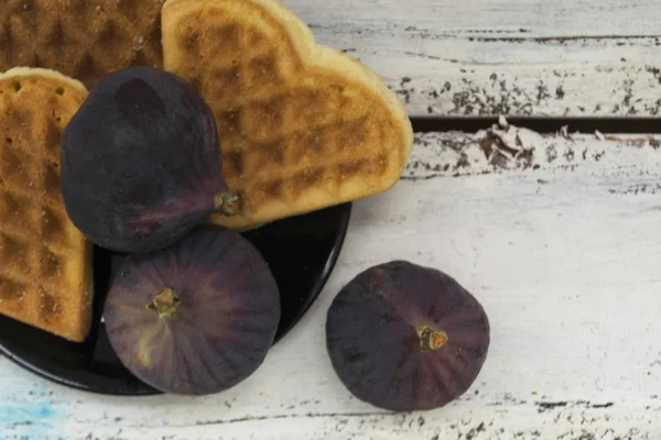 Kalp şeklinde kurabiye ler ile bir tabak üzerinde incir. Beyaz ahşap arka plan. Sonbahar konsepti.