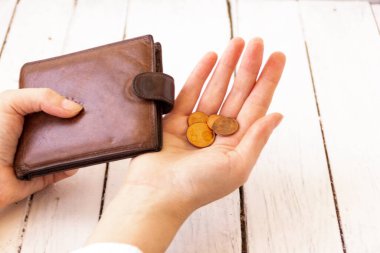 Boş bir cüzdana bozuk para döken bir adam. Kadın eli boş bir çanta, başka bir elde bozuk para, önemsiz bir şey. İşsizlik kavramı. Beyaz arkaplan