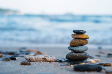 Çakıl taşları deniz kıyısındaki volkanik bir kayanın üzerine yığılır. Zen konsepti. Boşluğu kopyala.